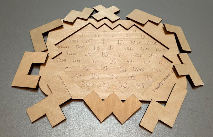 Photo of an empty board of calendar puzzle "Rhombus" with all 10 pieces around it